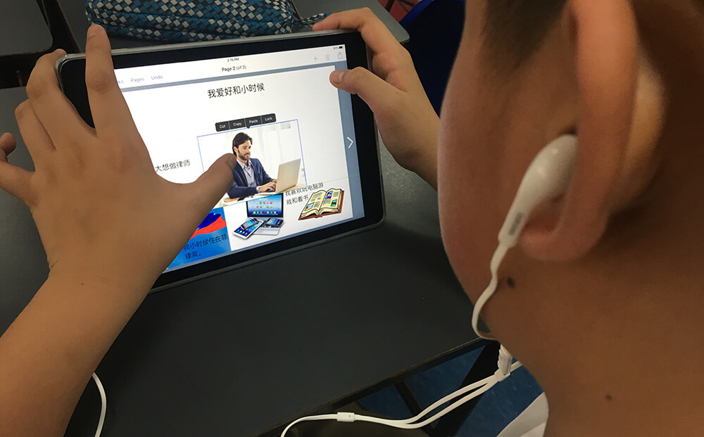 A boy, wearing headphones, working on his ebook