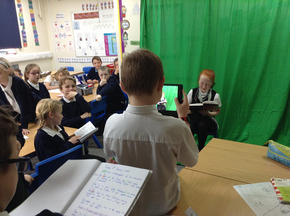 Students filming with a green screen background